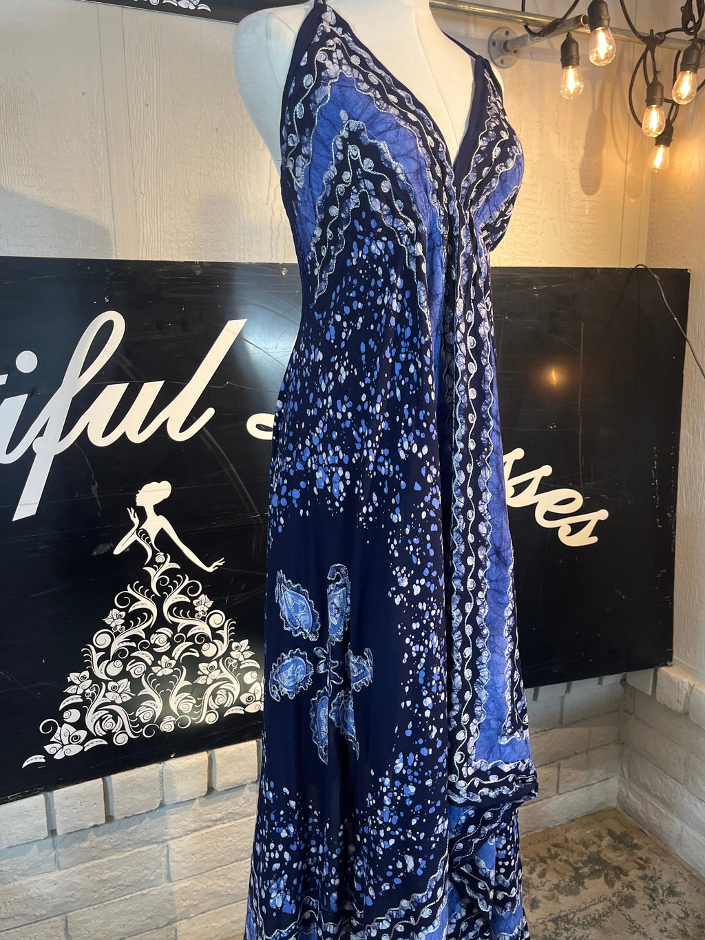Blue patterned dress on a mannequin against a black background with white text.